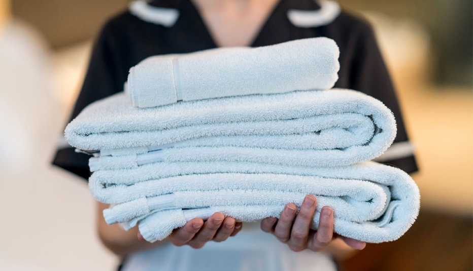 una empleada de limpieza en un hotel sujeta toallas limpias