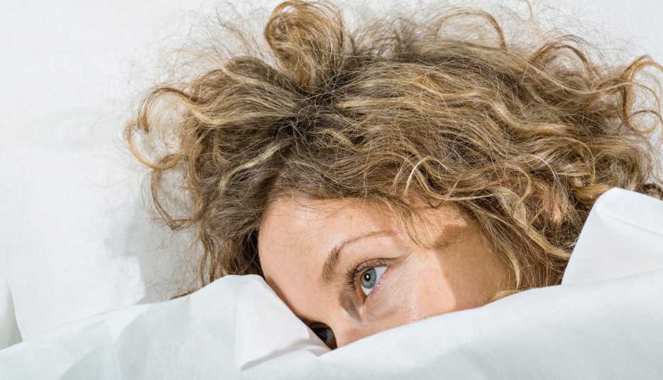 Una mujer acostada en su cama sin poder dormir