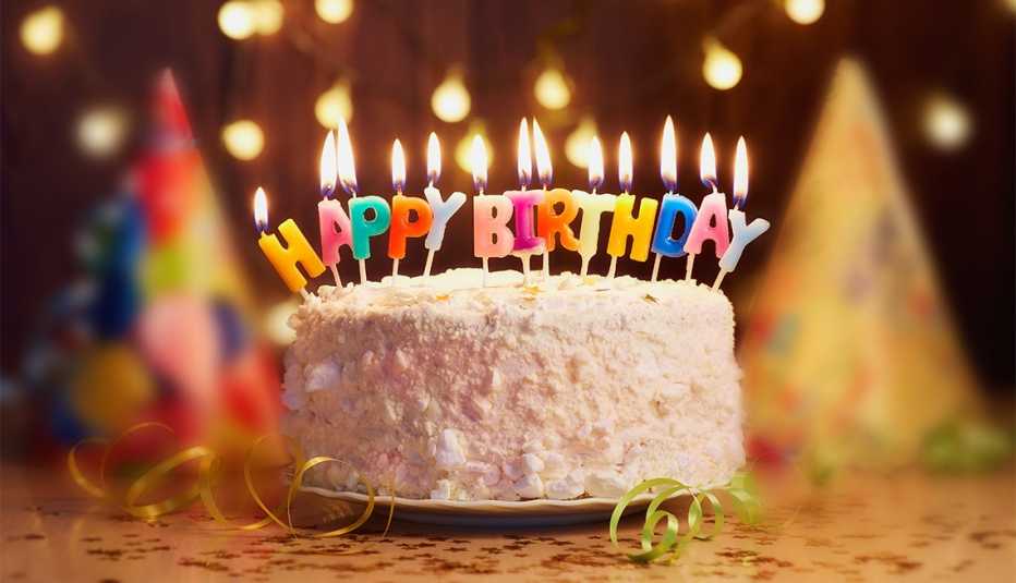Pastel de cumpleaños con velas y otras decoraciones en una mesa