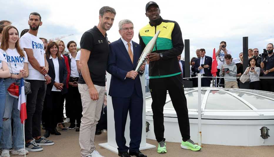 Tony Estanguet (izquierda), presidente de París 2024, y el exvelocista Usain Bolt, de Jamaica, sostienen la antorcha olímpica durante una gira preolímpica por el río Sena.