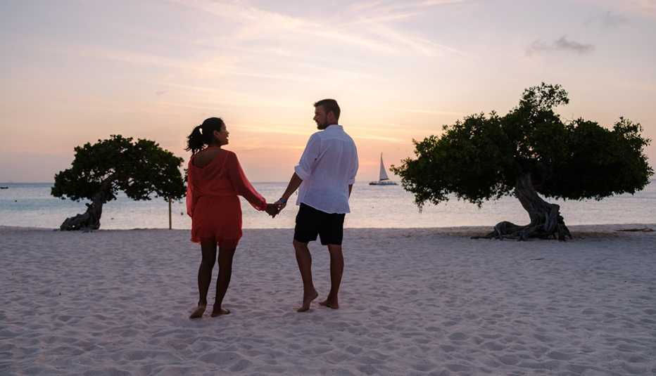 Una pareja tomados de la mano mientras estaban en la playa de Aruba.