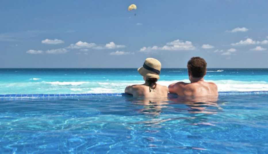 Dos personas en una piscina con vista al mar