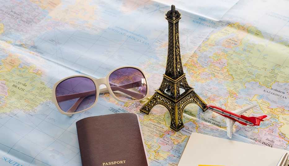 Pasaporte, lentes oscuros, réplica de la Torre Eiffel y avión a escala sobre un mapa