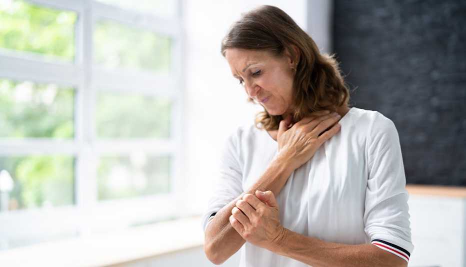 mature woman itching her arm and looking uncomfortable