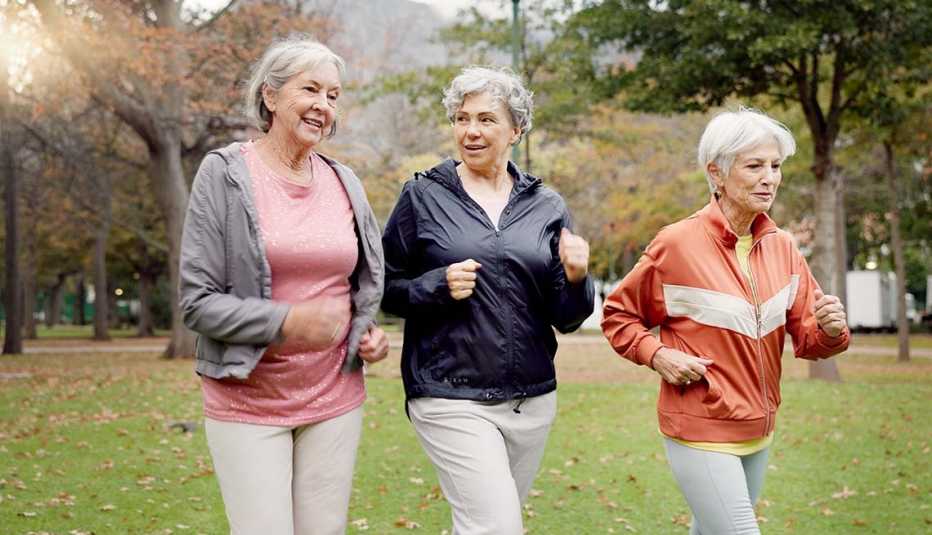 Three older adults walking together in a park during autumn
