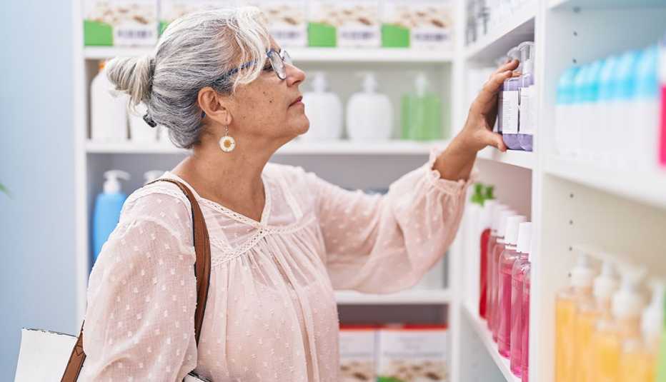 Middle age grey-haired woman customer looking shelving at pharmacy