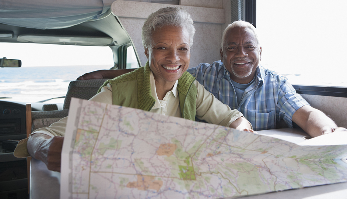 couple seated in camper looking at a map