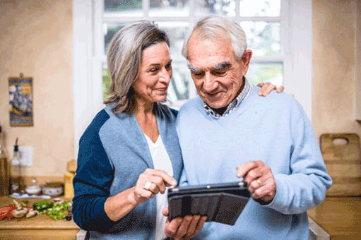 older man and woman couple in kitchen reading a tablet