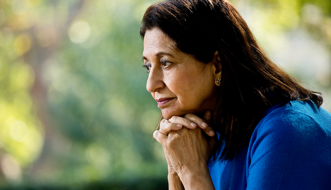 Woman with brown hair and brown eyes wearing blue shirt looking distressed