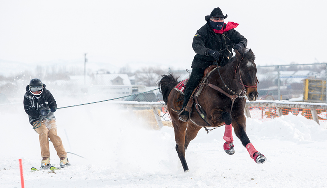 man on a horse towing a skiier. this sport is called skijoring.