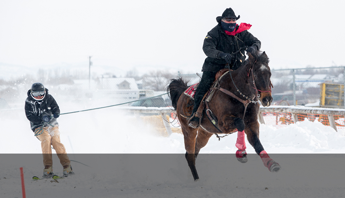 skijoring - a horseback rider towing a skiier in the snow