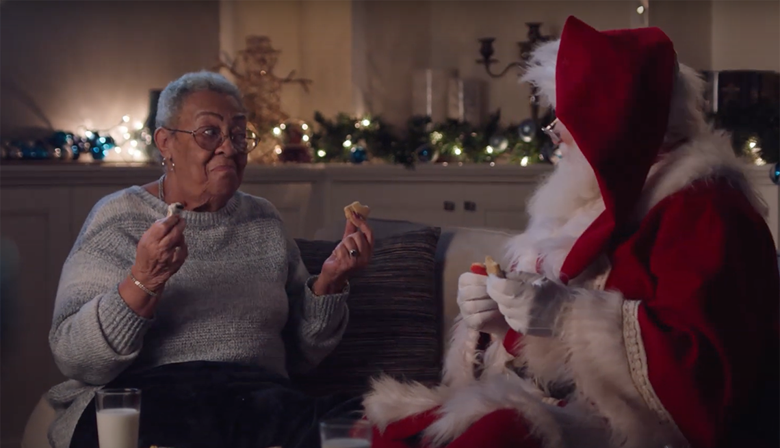 Señora mayor platicando y comiendo galletas con Santa Claus