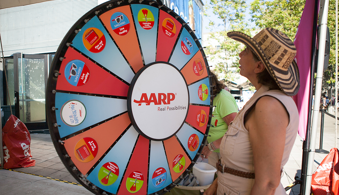 Woman spinning a prize wheel at an A A R P block party event
