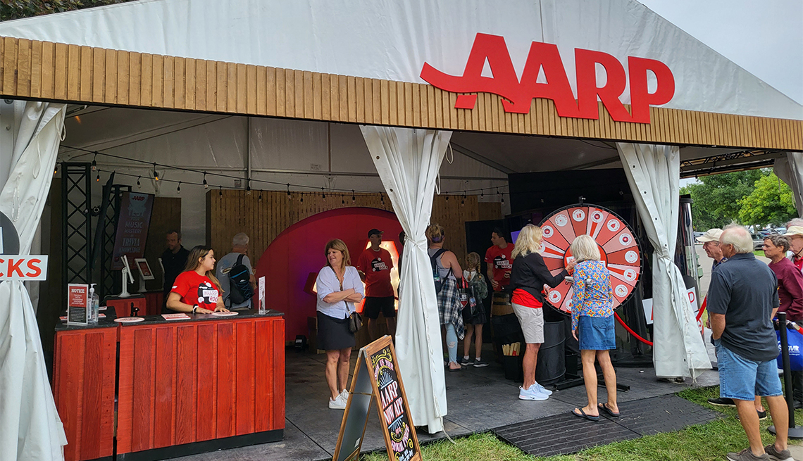 a group of people standing in an a a r p event tent looking at a prize wheel