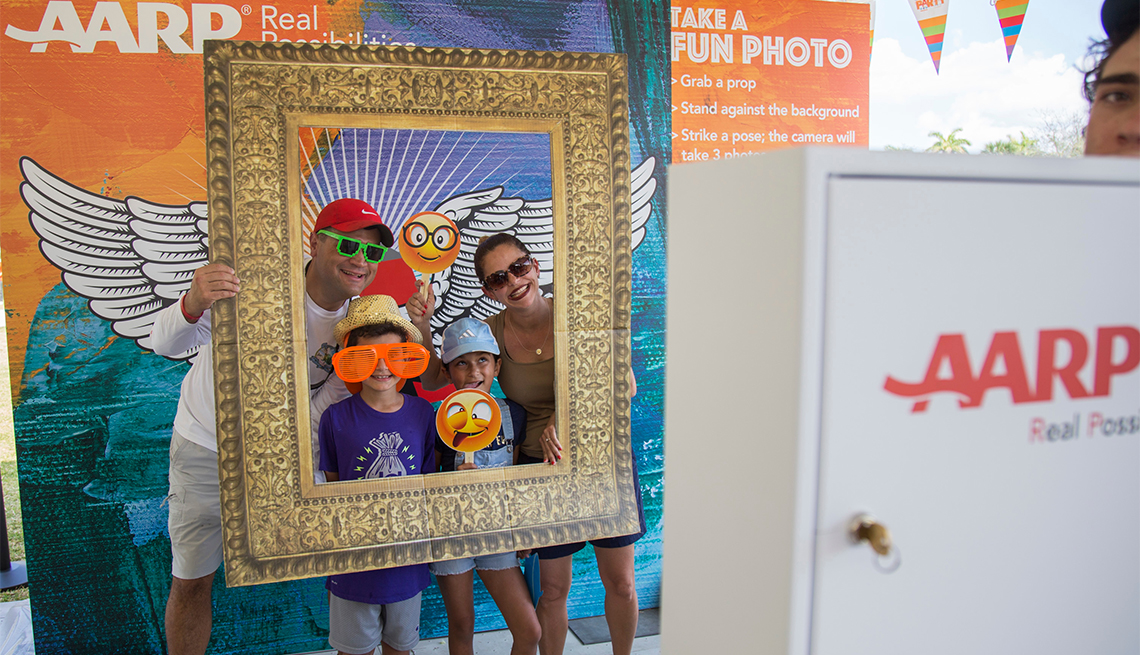 two adults and two children posing behind a large picture frame at an a a r p event