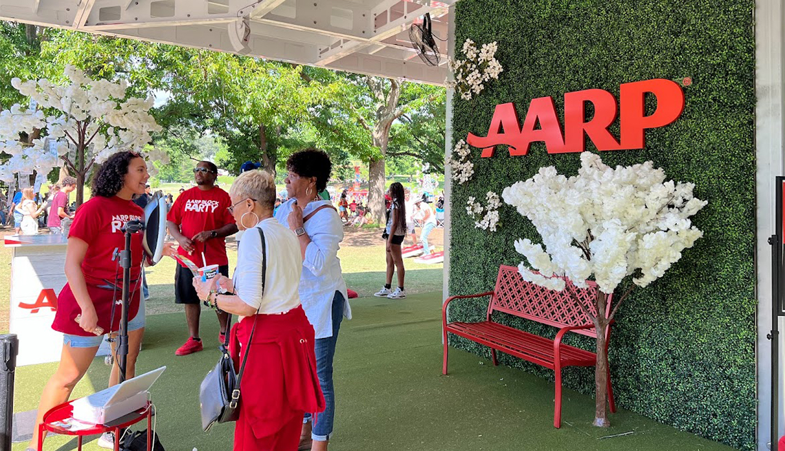 Women talking near a grass covered wall with an a a r p logo on it at the artscape event in baltimore