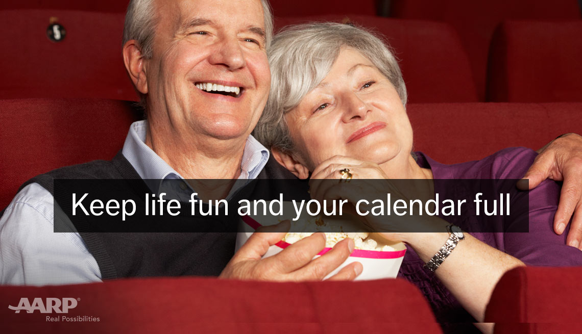 A caucasian middle aged couple eat popcorn in movie theater with text that reads keep life fun and your calendar full.