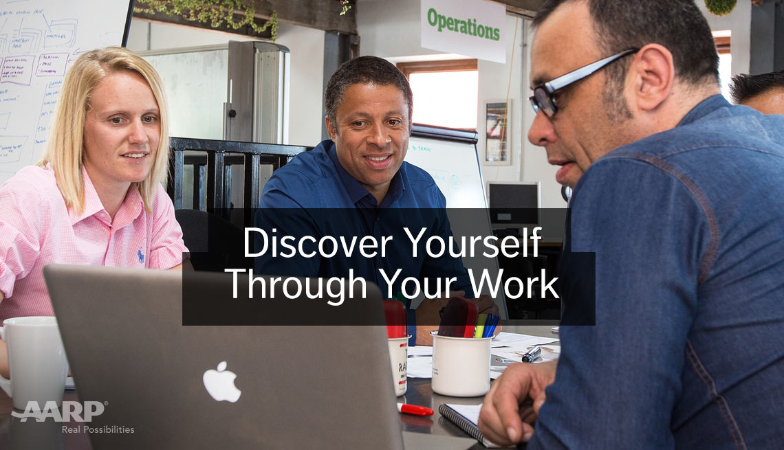 Discover yourself through your work. Two seated men and a woman look at apple laptop screen in office