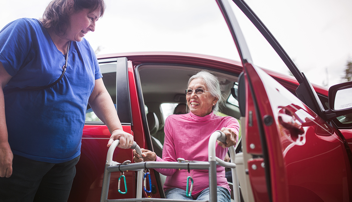 Qué deberían tener los automóviles para cuidadores - Mujer baja de un carro ayudada por un caminador