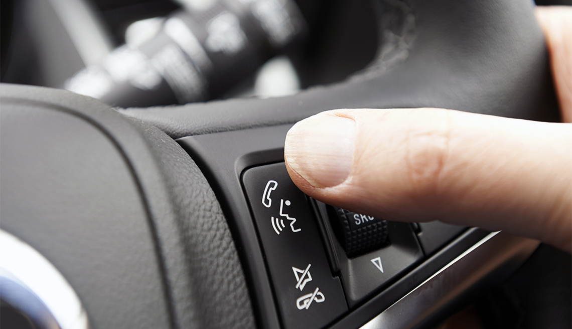 La mano de una persona controla el botón de bluetooth en el volante de un automóvil.