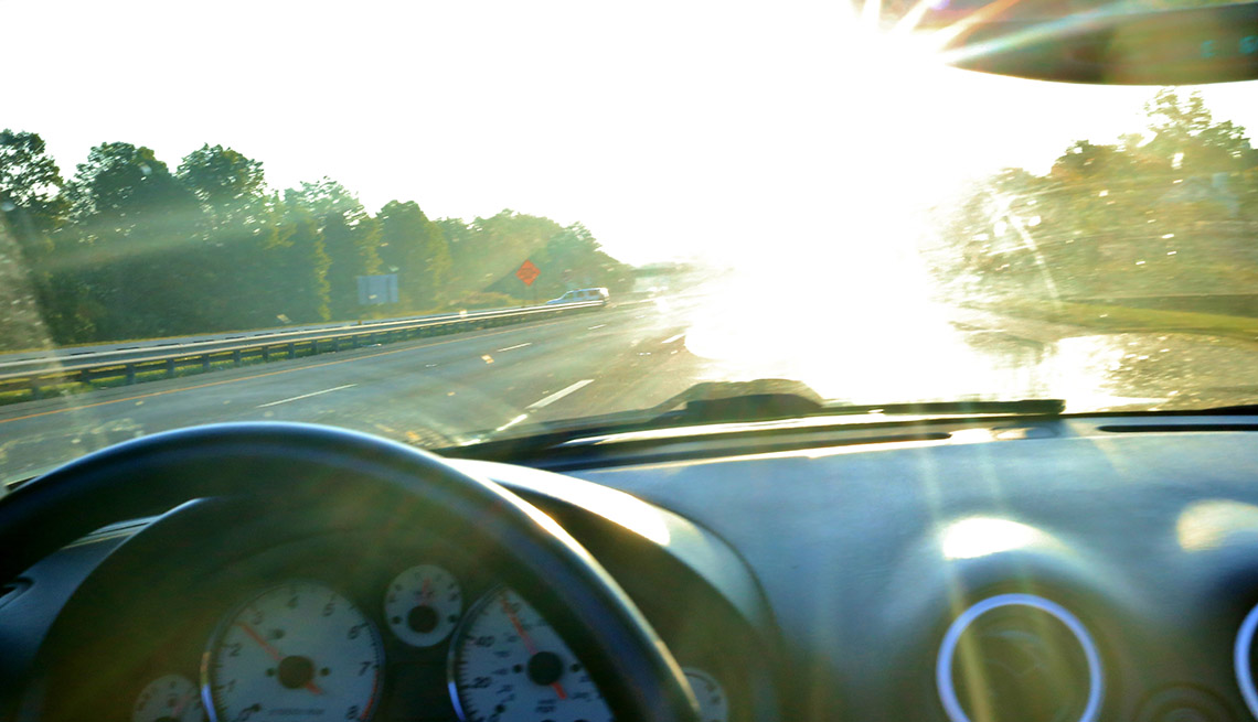 El resplandor del sol se ve desde un auto en el horizonte.