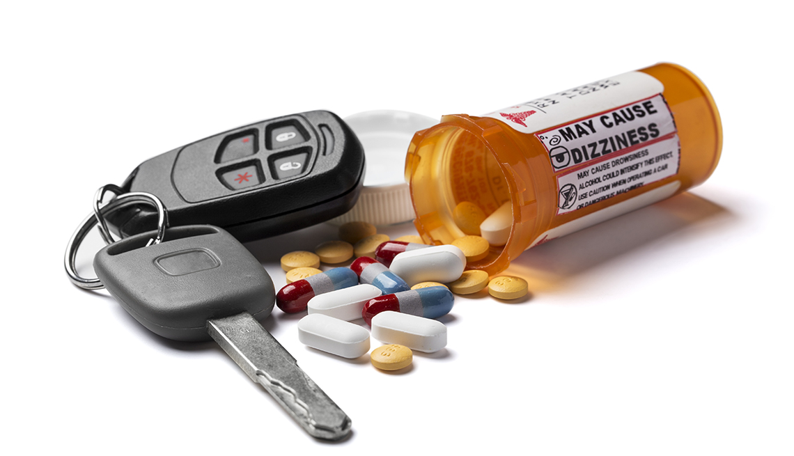 Llaves de automóvil junto a una botella de medicamentos y pastillas de colores.