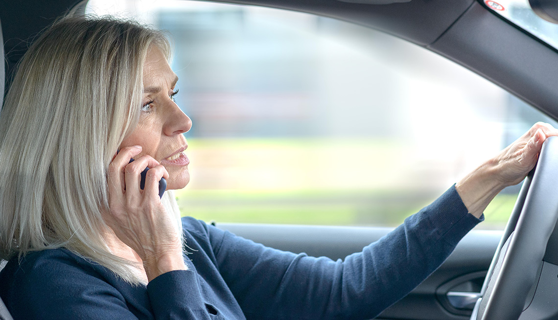Mujer habla por teléfono mientras conduce un automóvil