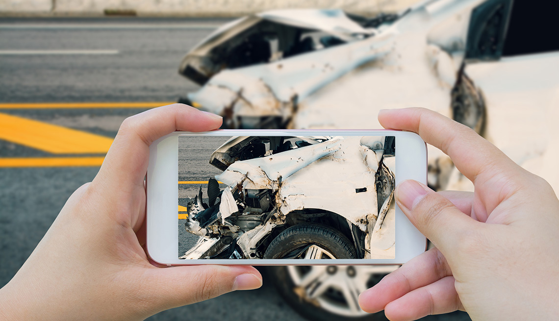 Mujer toma una foto con un teléfono inteligente de un accidente automovilístico en la carretera