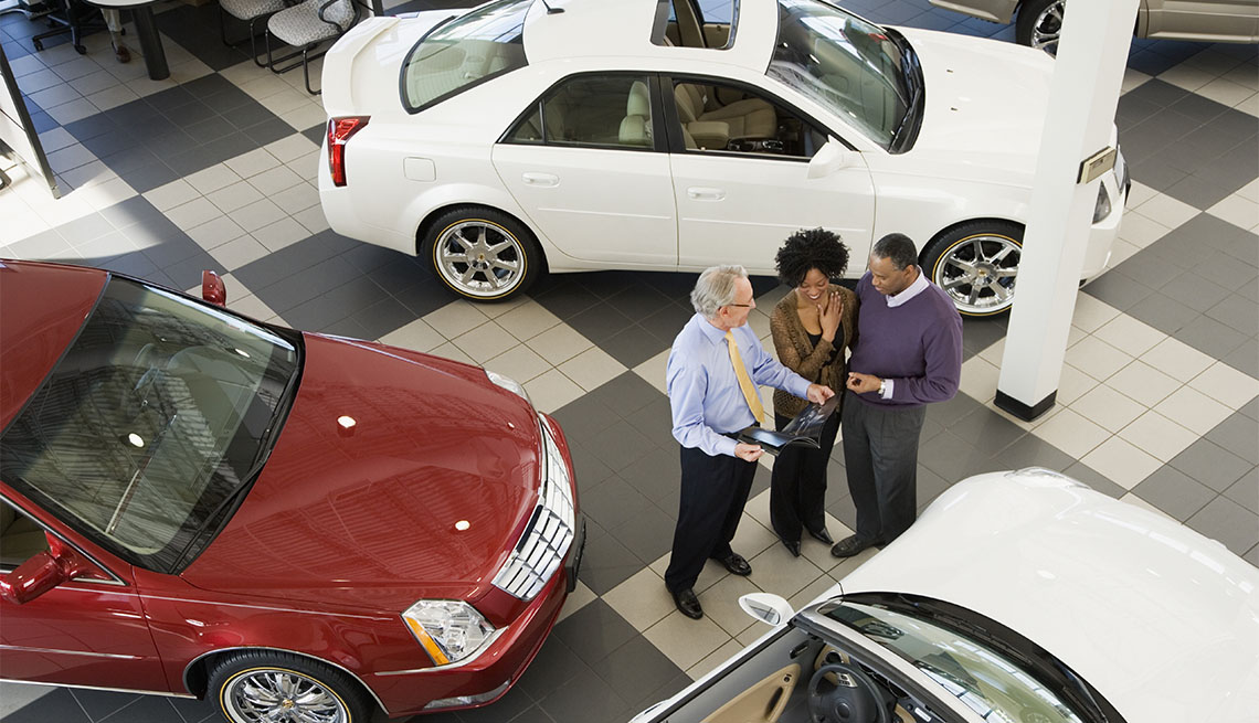 couple talking to a salesman at a car dealership