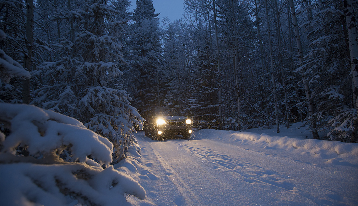 Auto conduce en la carretera cubierta de nieve entre las montañas