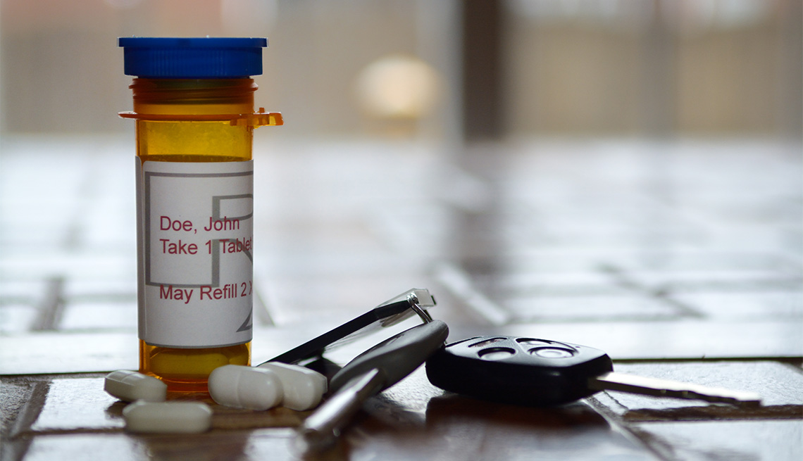 Frasco de medicinas junto a algunas pastillas y las llaves de un auto