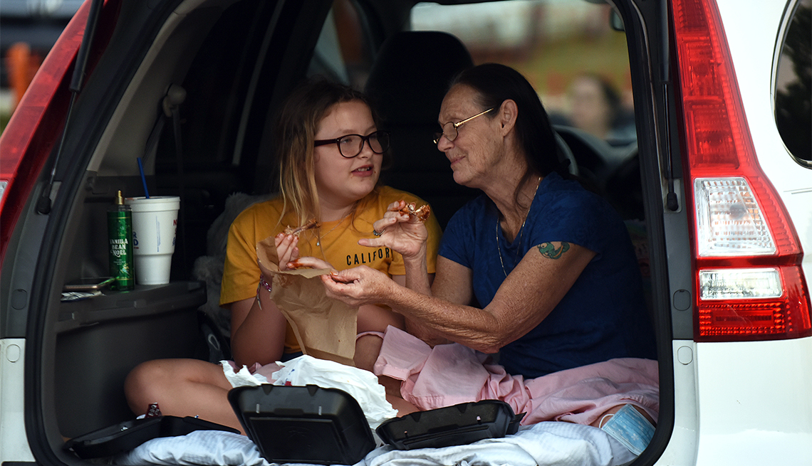 Dos mujeres comen en la parte trasera de un auto en el autocine