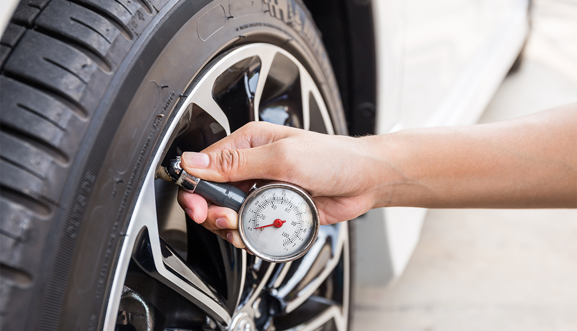 close-up of hand holding tire pressure gauge 
