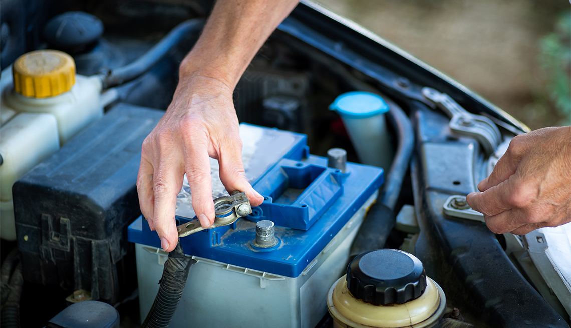 Man connecting the car battery to the vehicle with a wrench 