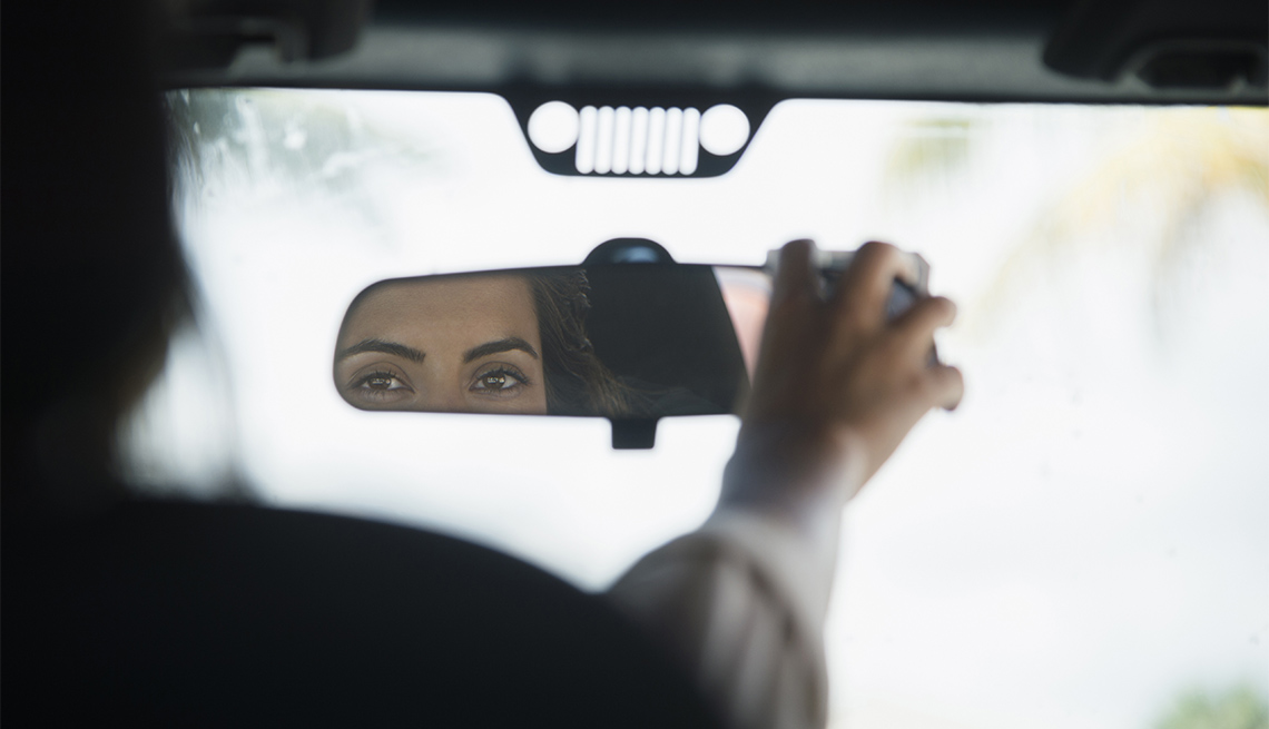 woman adjusting rear view mirror in car