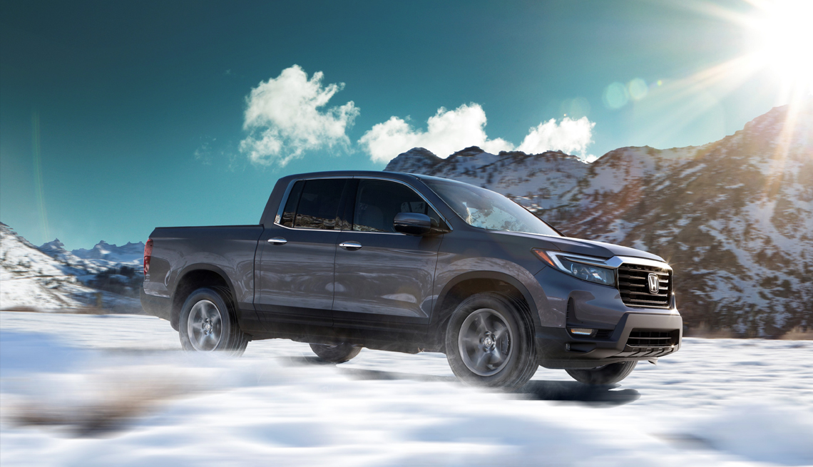 a picture of a twenty two honda ridgeline driving through snowy mountains