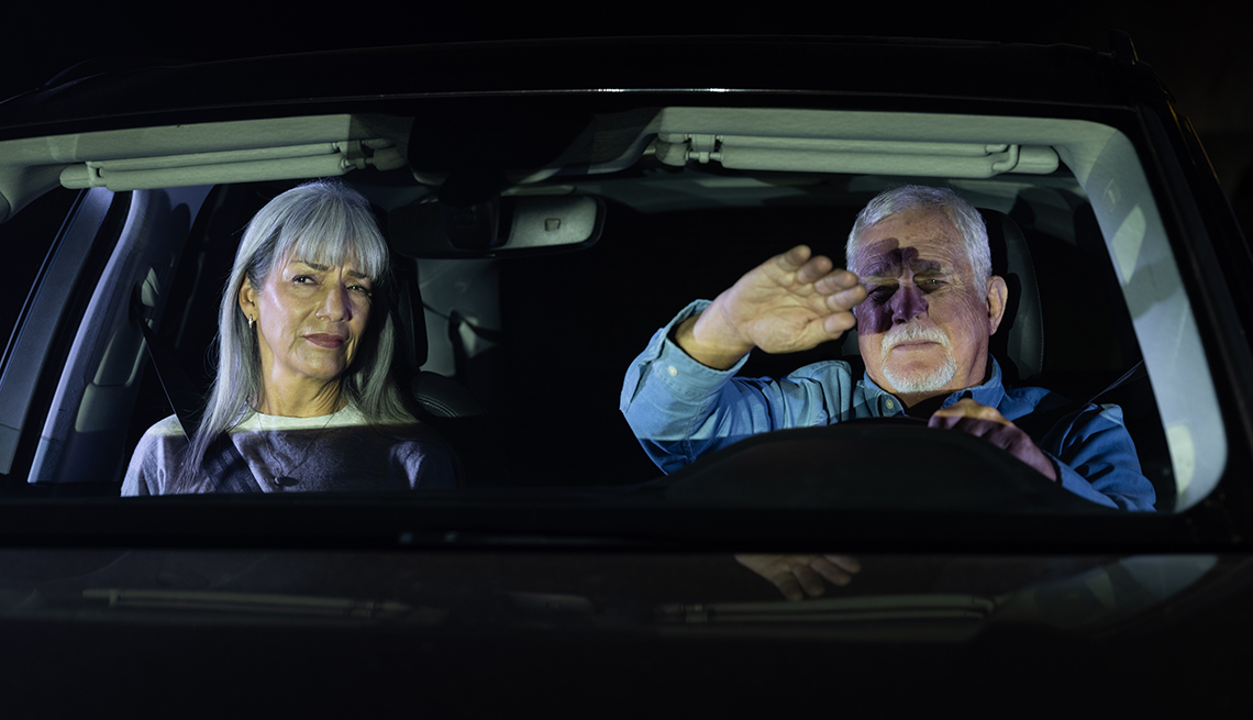 a man and a woman driving at night are blinded by an oncoming car with its brights on