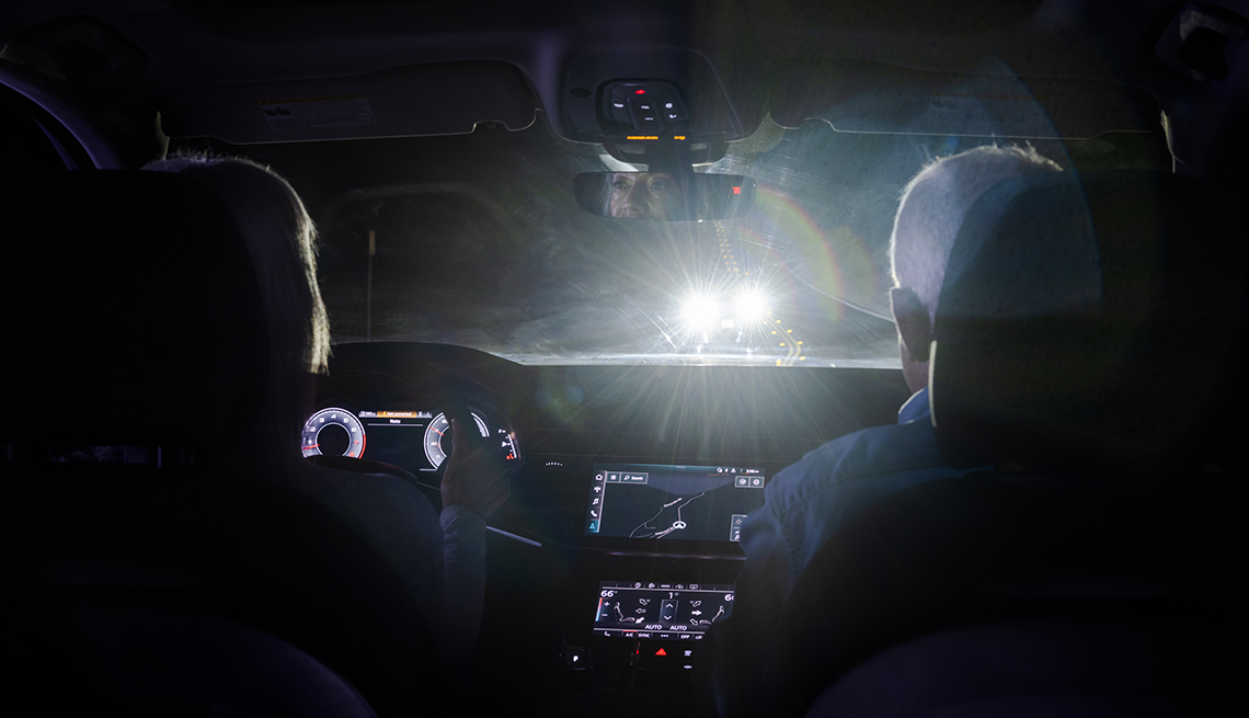Una pareja conduce en la oscuridad, mientras otro vehículo los alumbra de frente