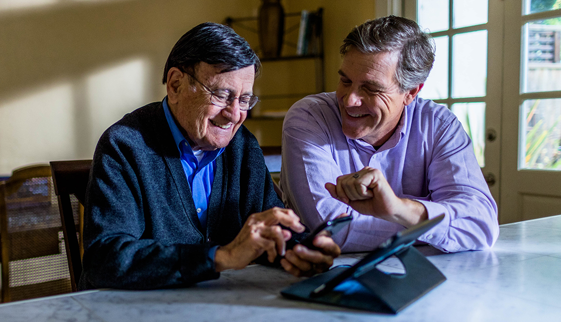 Dos hombres sentados con una tableta y un teléfono celular