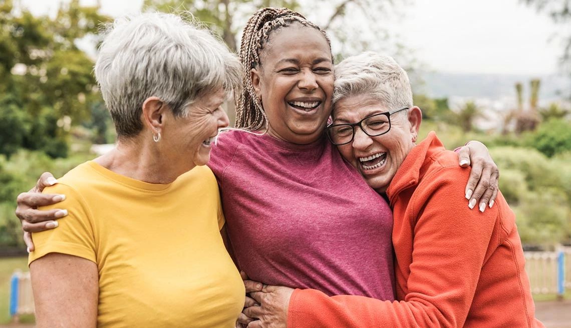 Group of mature women hugging wearing workout clothes outdoors