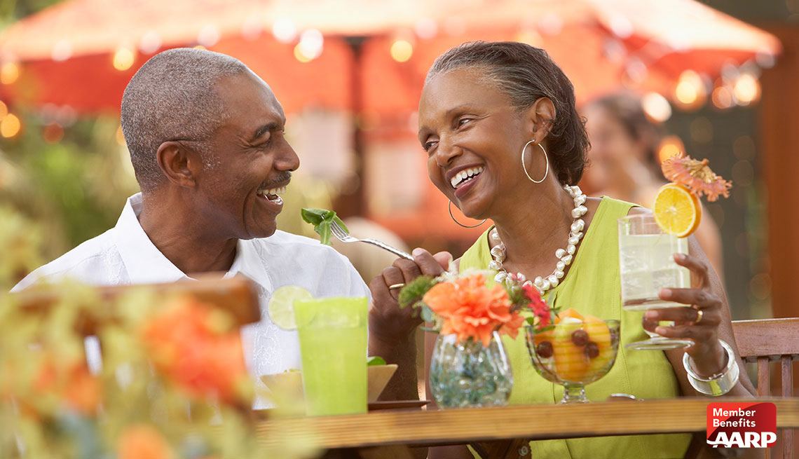 african american couple eating at bar with drinks and smiling