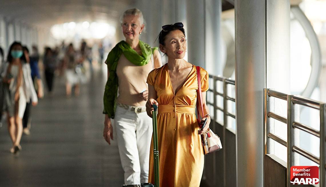 two women in airport with luggage on walkway