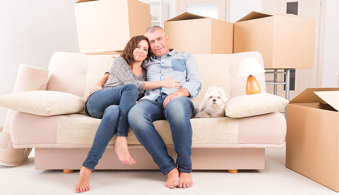 Una pareja sentada en un sofá en su nueva casa delante de cajones de cartón