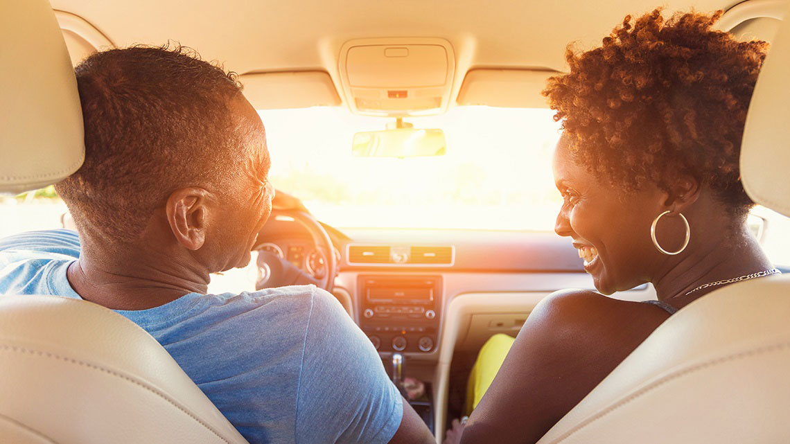 couple inside car smiling at sunset