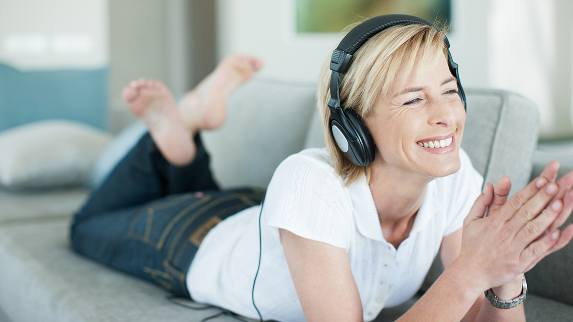 Smiling woman on couch listening to headphones