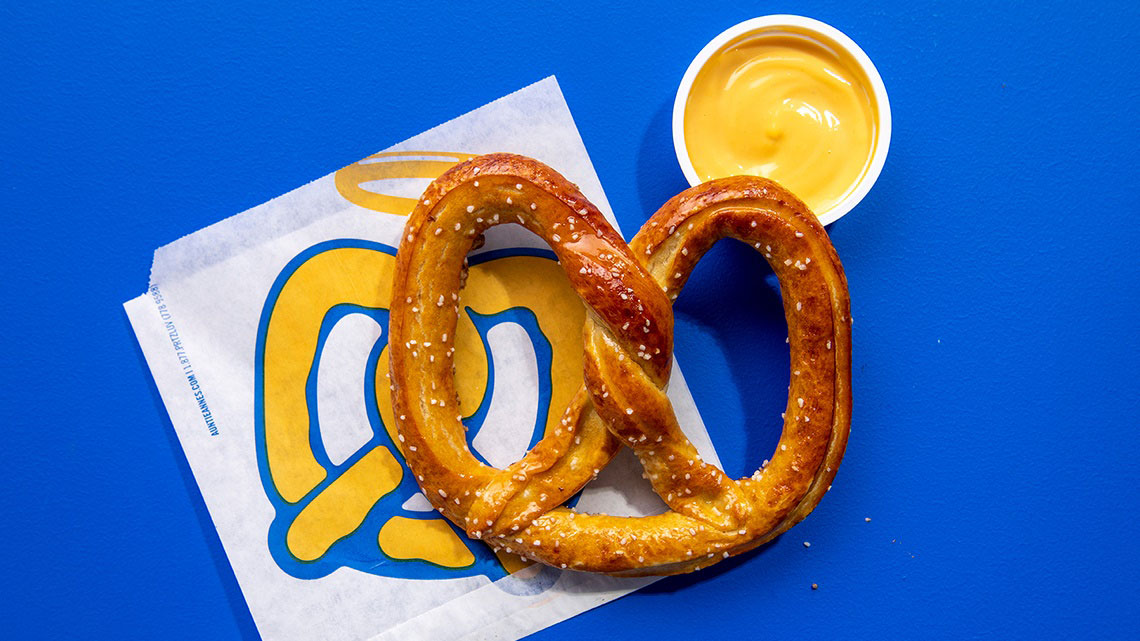 Pretzel on bag with cup cheese dip blue background