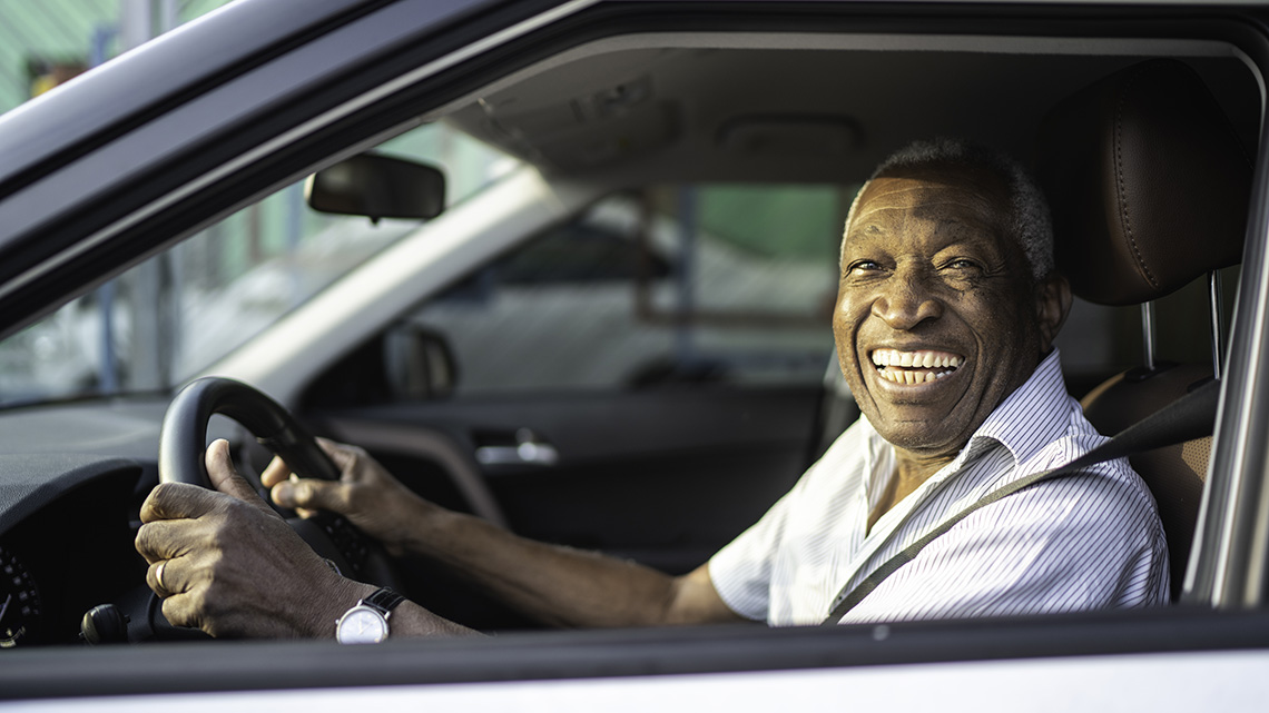 Smiling senior afro man driving a car and looking at camera