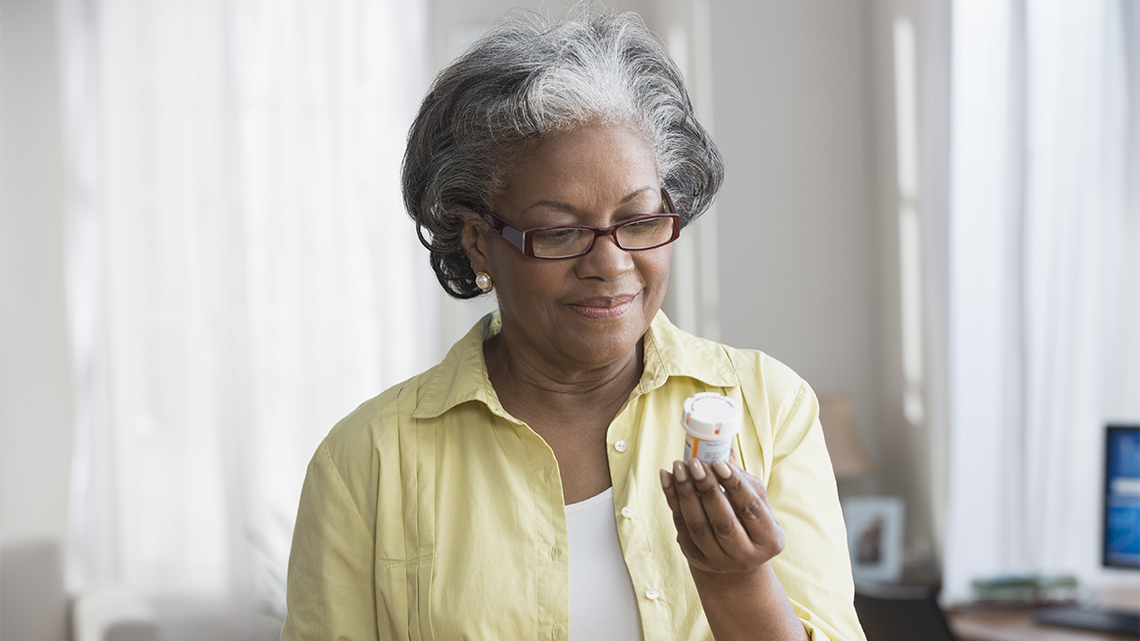 Mature African American woman holding prescription bottle