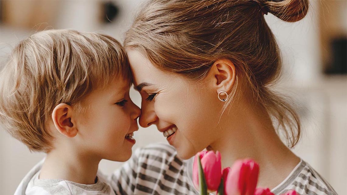 happy mother's day! child son congratulates mother on holiday and gives flowers