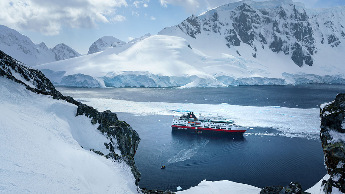 large cruise ship in cold weather with snow cap mountains in the background